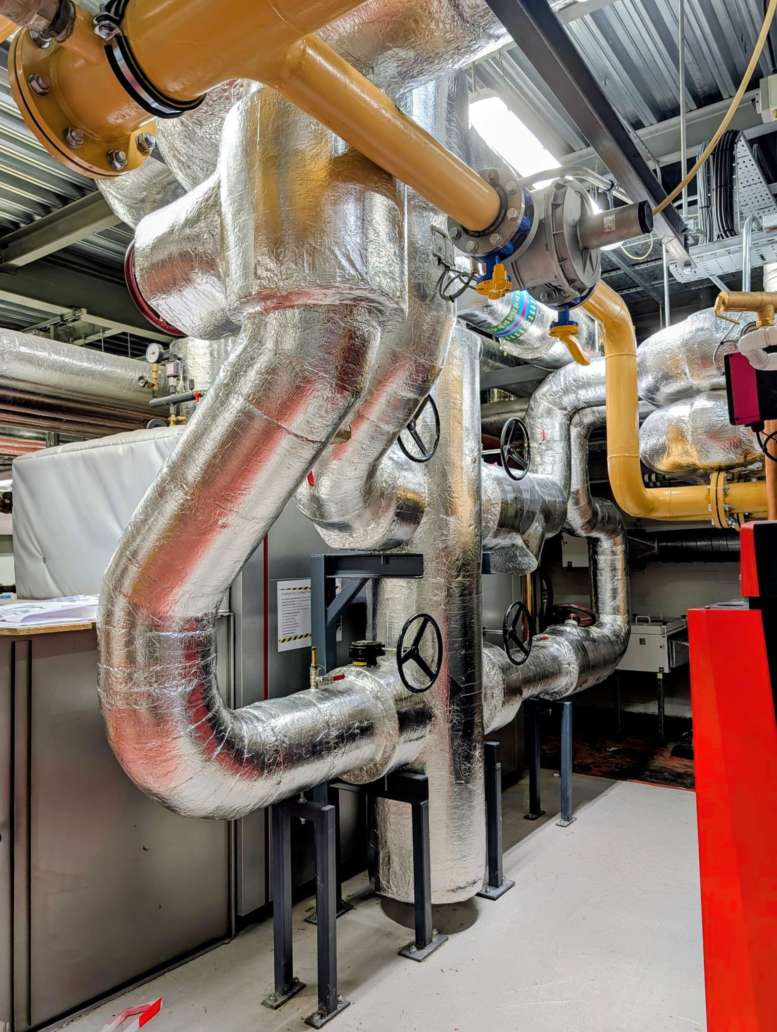Insulated mechanical plant room with pipework, valves, and flanges — Alumitherm Assist